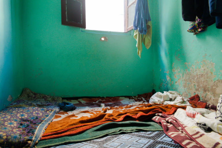 A mattress and blankets lie on the floor of a modest room shared by a young mother and her child in Casablanca.