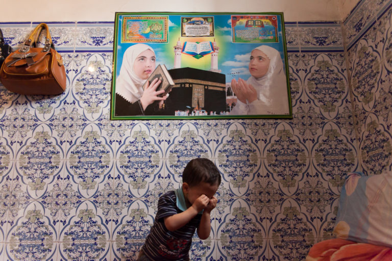 A young boy cries beneath religious images in the modest room he shares with his mother in Casablanca.